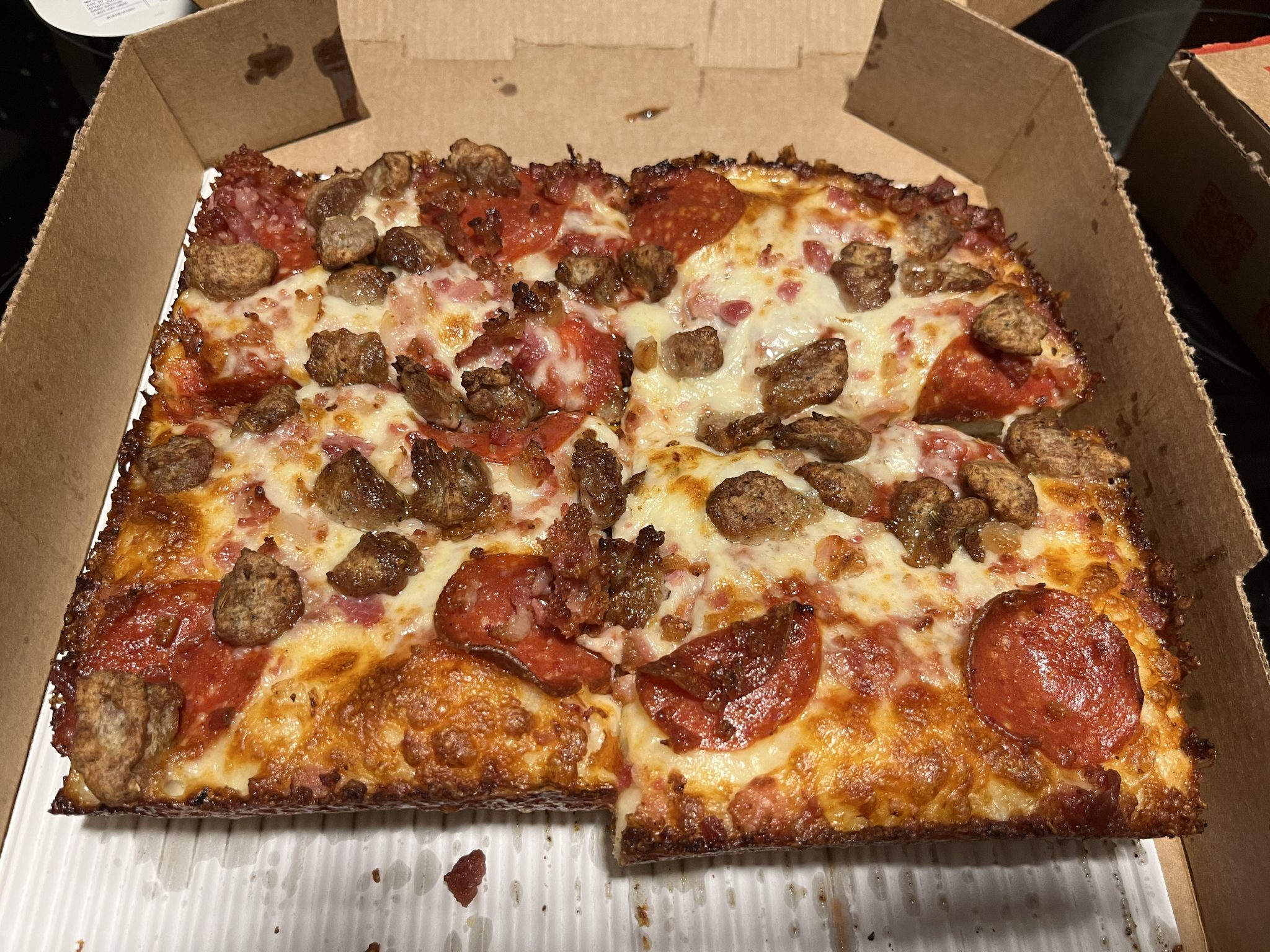Pizza, square, thick crust, crispy and square on the corners, pepperoni, italian sausage, bacon.