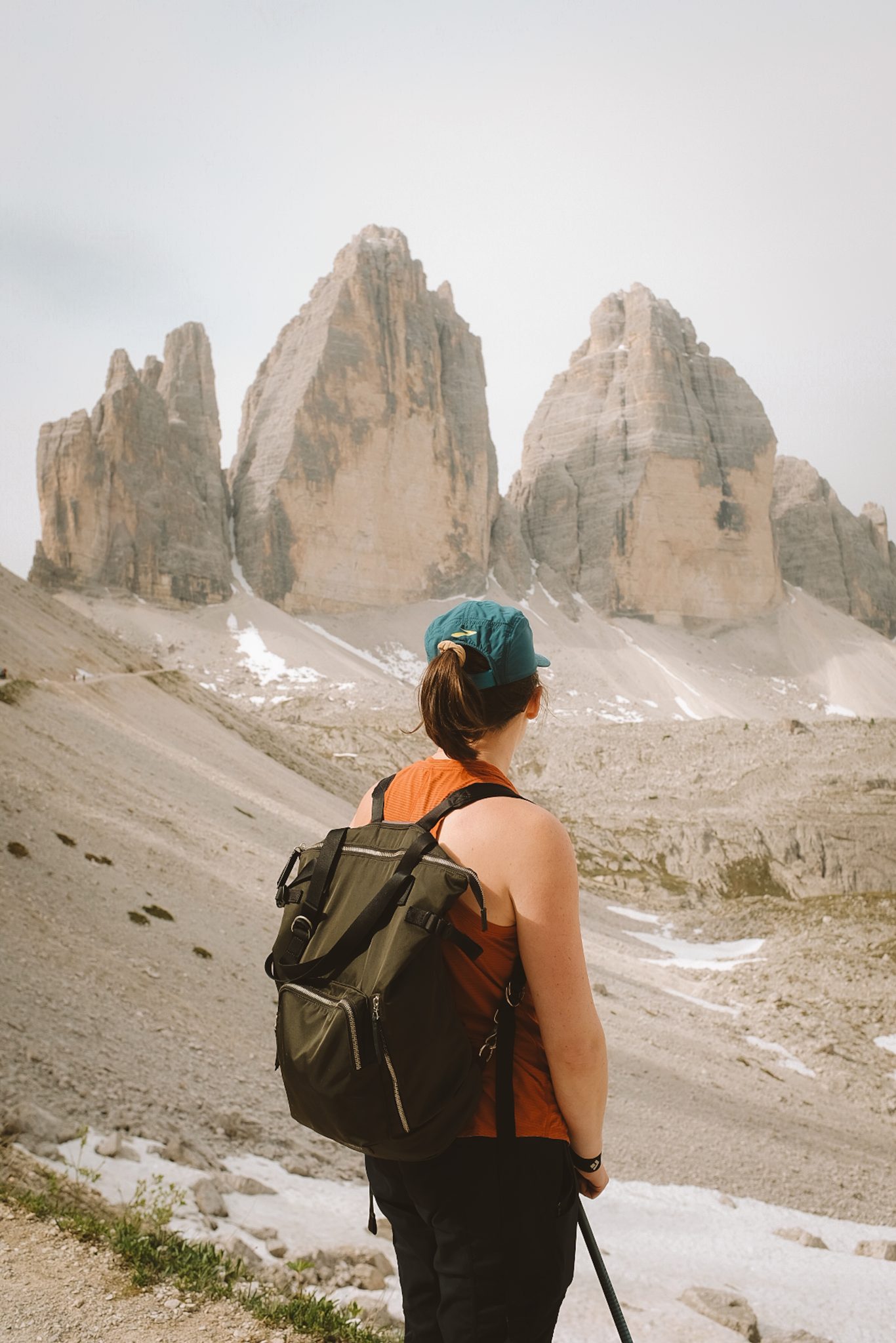 Person standing in front of three dolomite mountain peeks with back facing the camera looking out at the view.