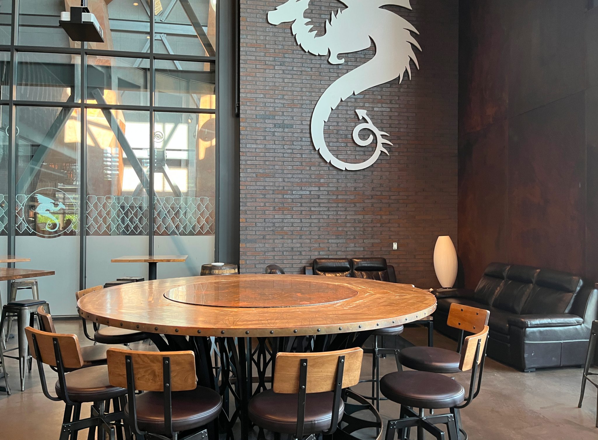 Round wooden table with a large steel dragon above it on the wall.