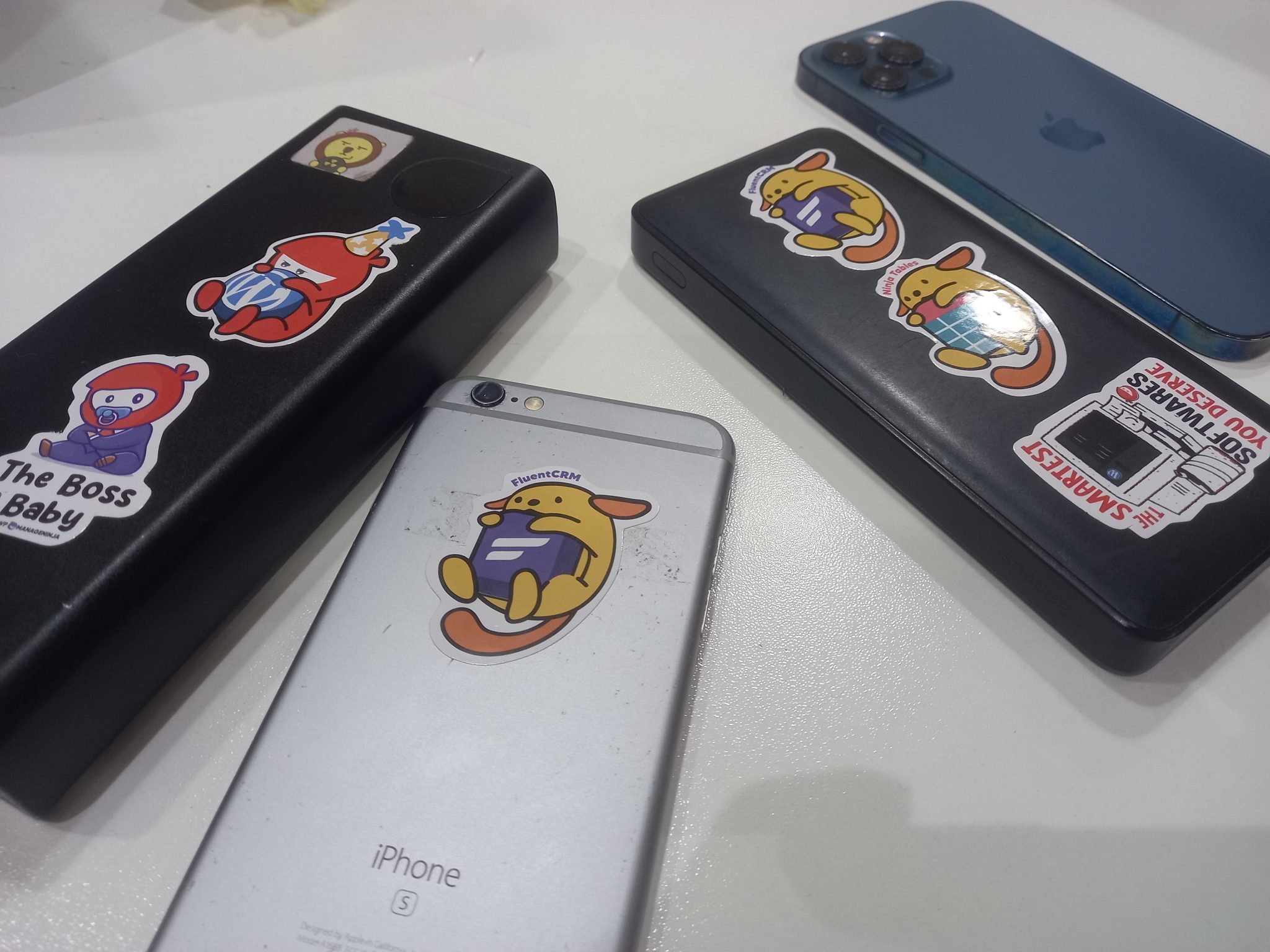 Two iphones and two external batteries with Wapuu stickers on them.