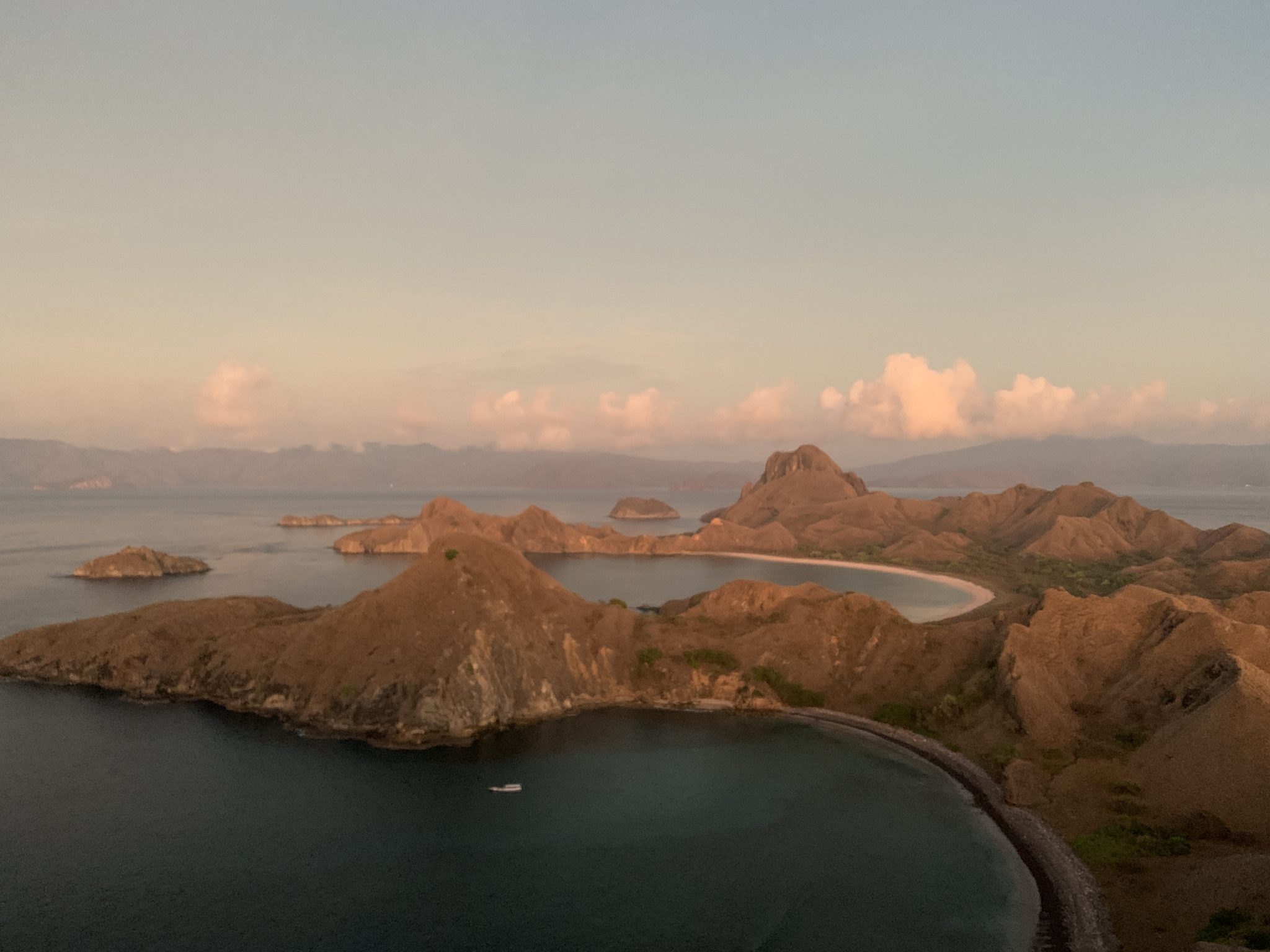 Morning view on Padar Island, Labuan Bajo, Indonesia. Long view of a rocky island with many inlets, puffy clouds on the horizon.