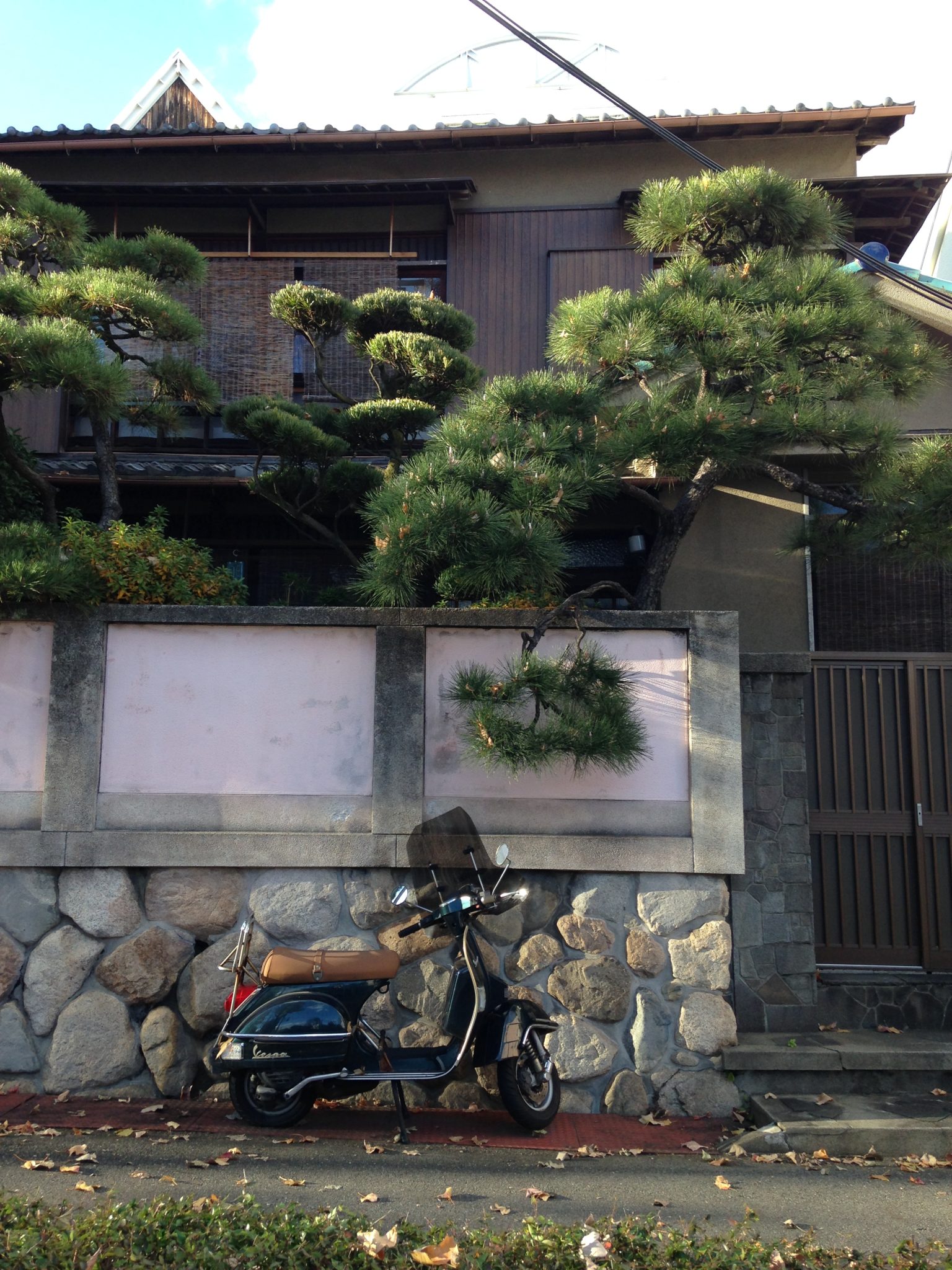 A Vespa motorbike in front of a Japanese house