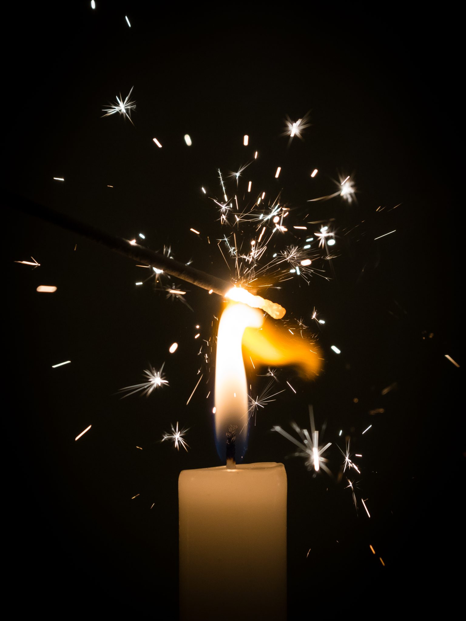 Detail of a sparkler being lit by a candle
