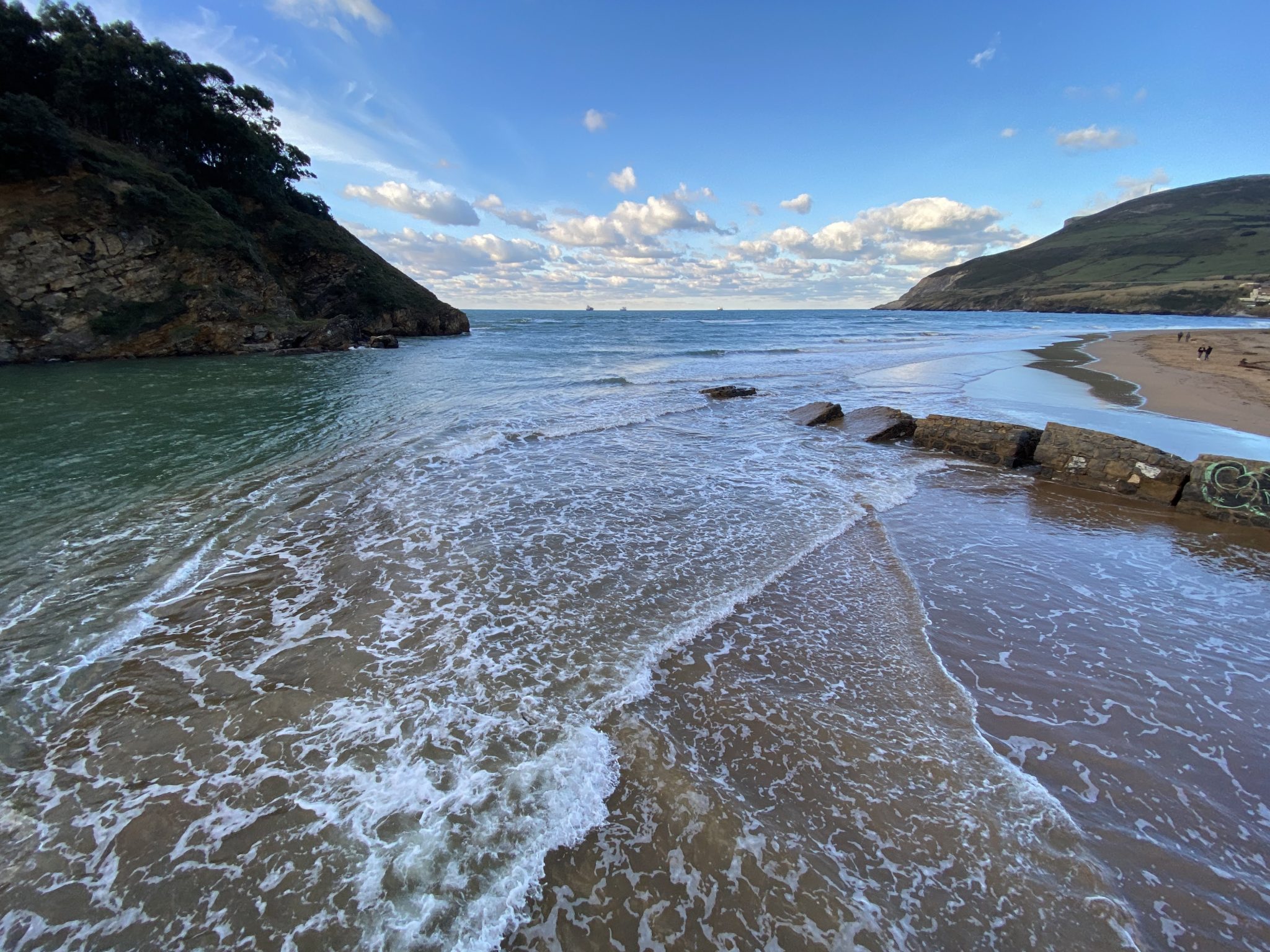 Panoramic photo of Pobeña in Bizkaia beach with the current of the sea waves reaching the sandy shore.