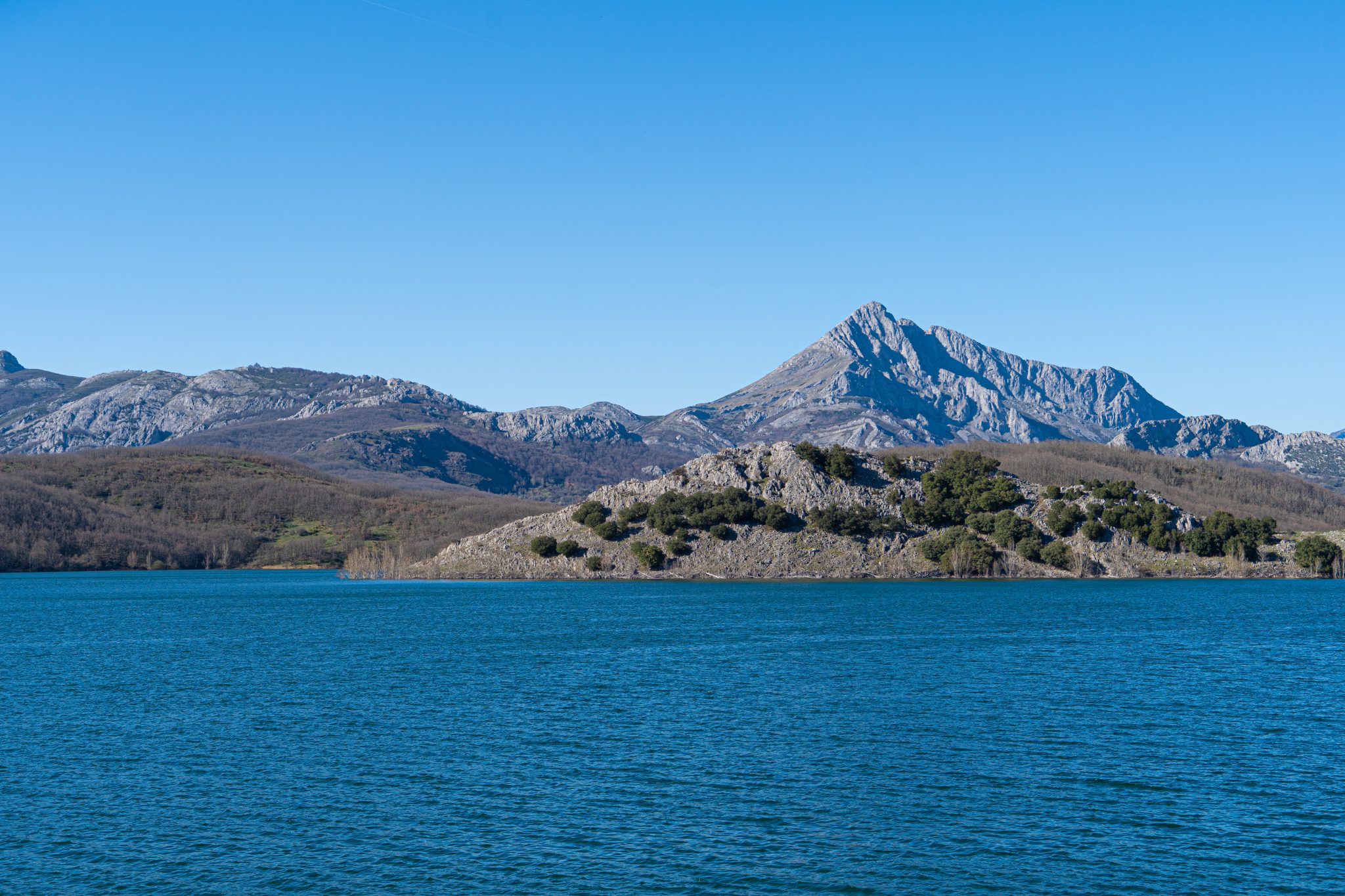 Picture of a blue lake surrounded by large mountains on a sunny day.