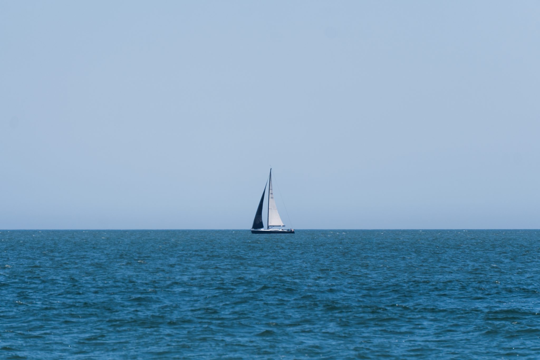 A sailboat in the distance on the horizon in the Atlantic Ocean