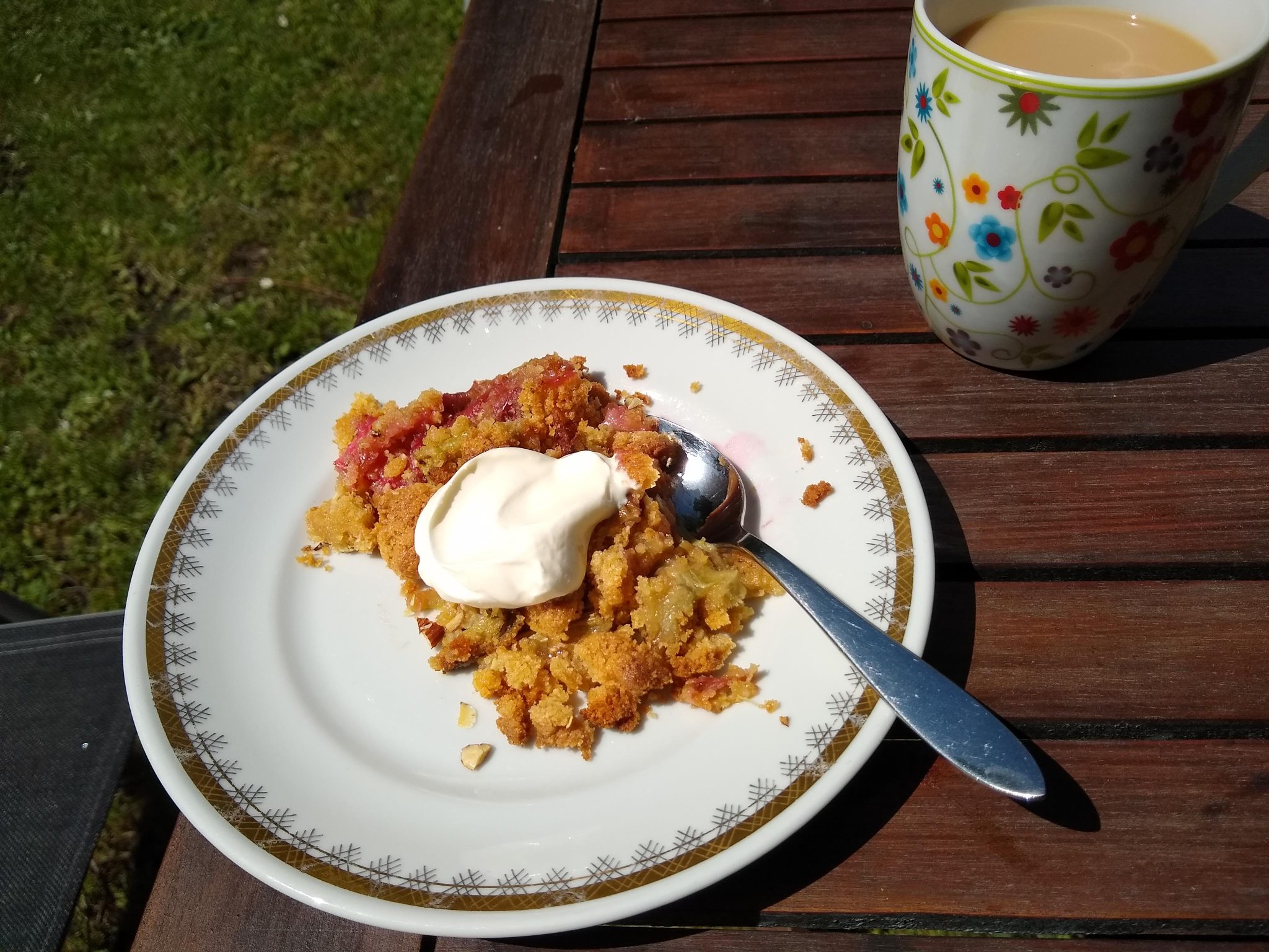 A plate of crumble and a cup of coffee on an outdoor garden table