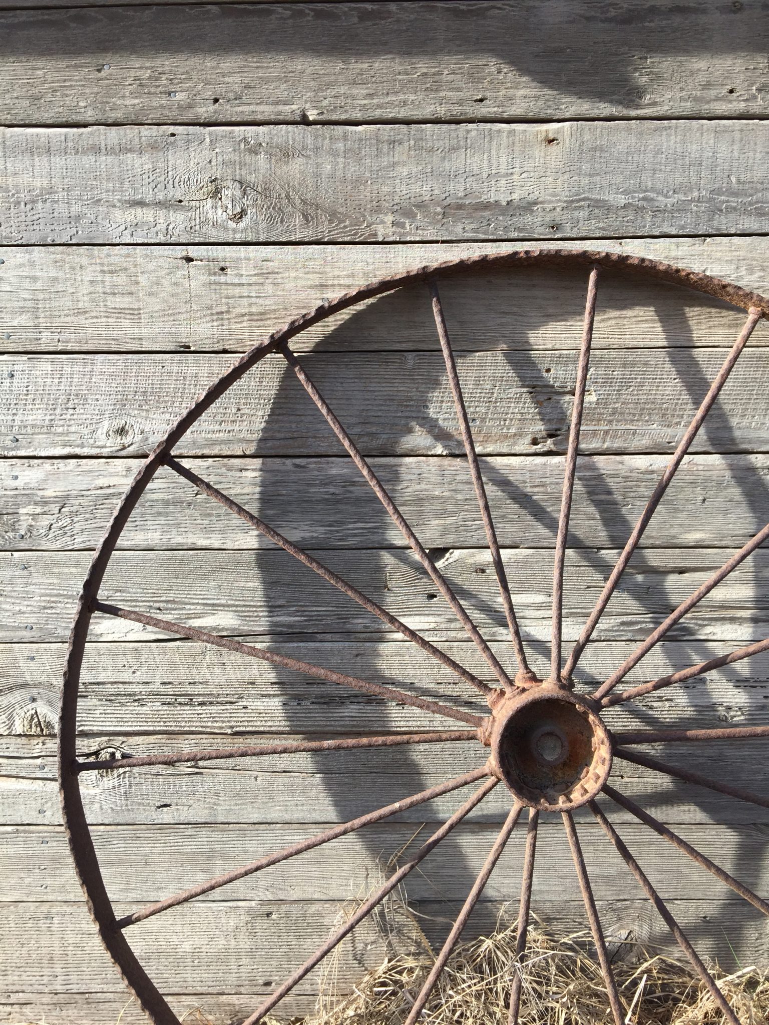 Metal wagon wheel against an old country barn wall