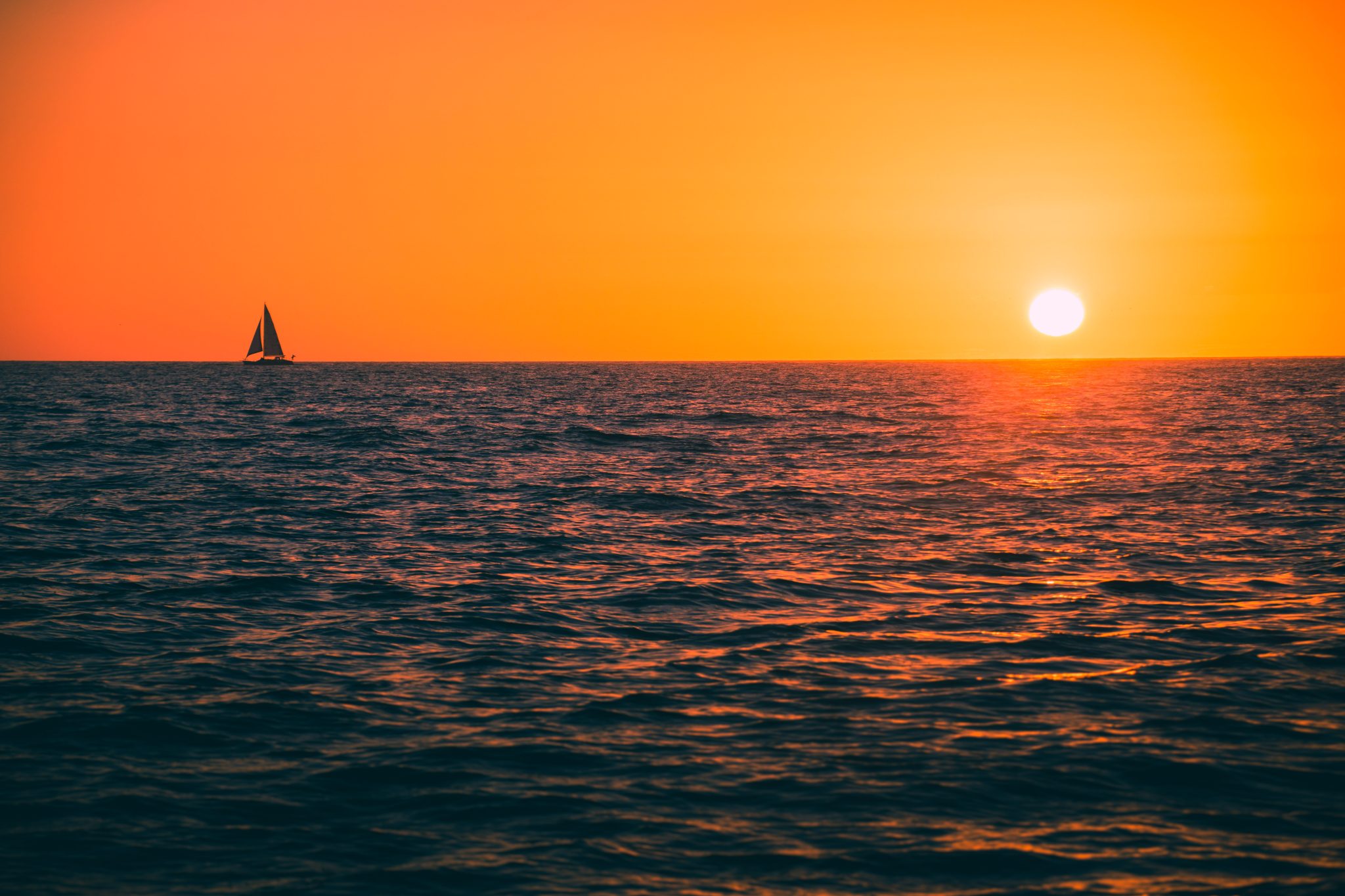 Single sailboat on the water at sunset