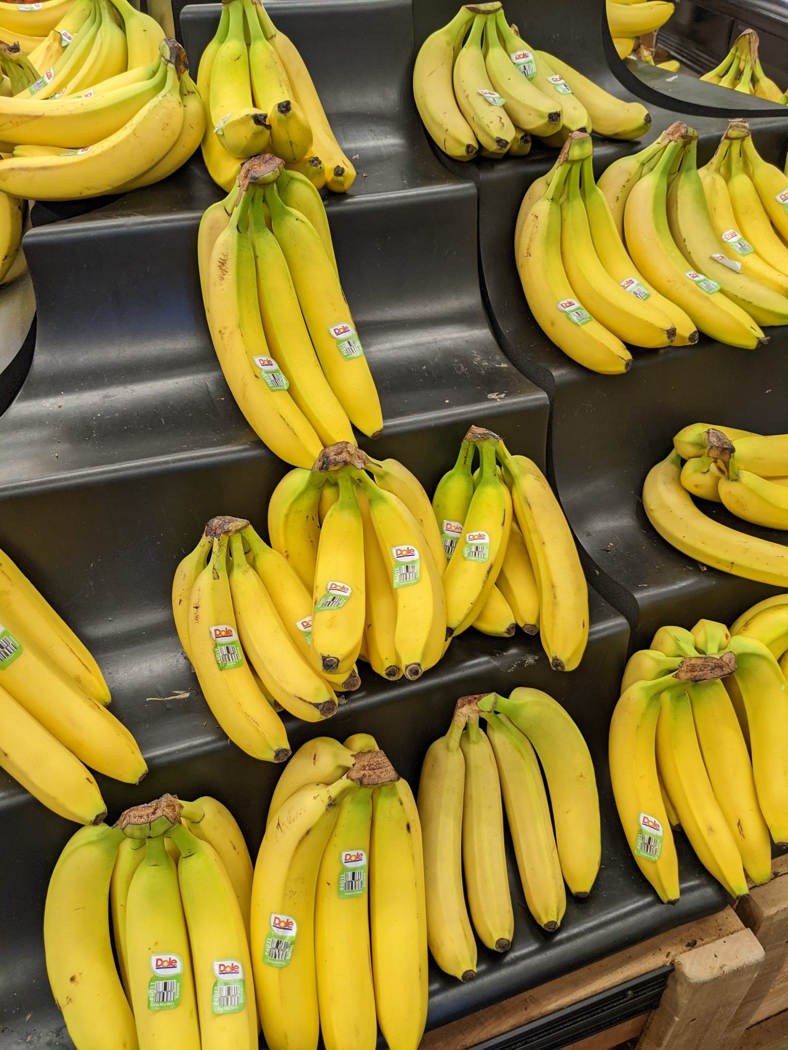 Several bunches of bananas on shelves in a store