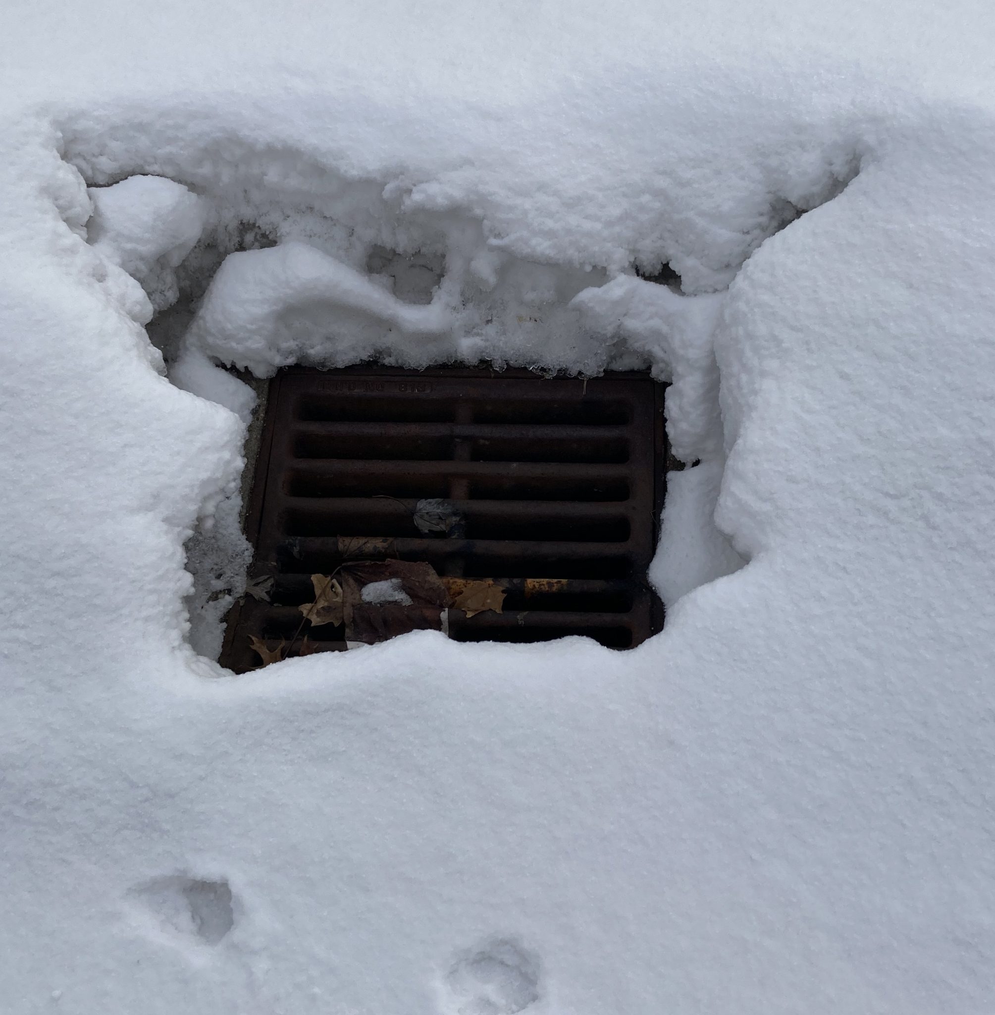 A snow covered street water drainage
