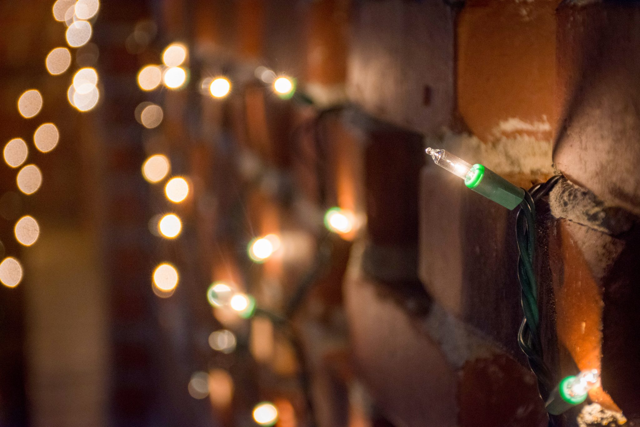 Small Christmas light on a brick wall with others in the background