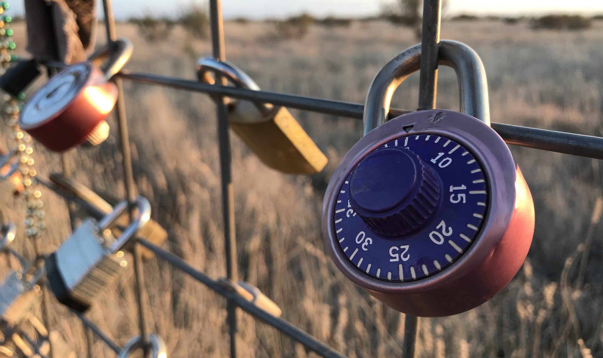 Security lock hanging on a metal fence in the desert