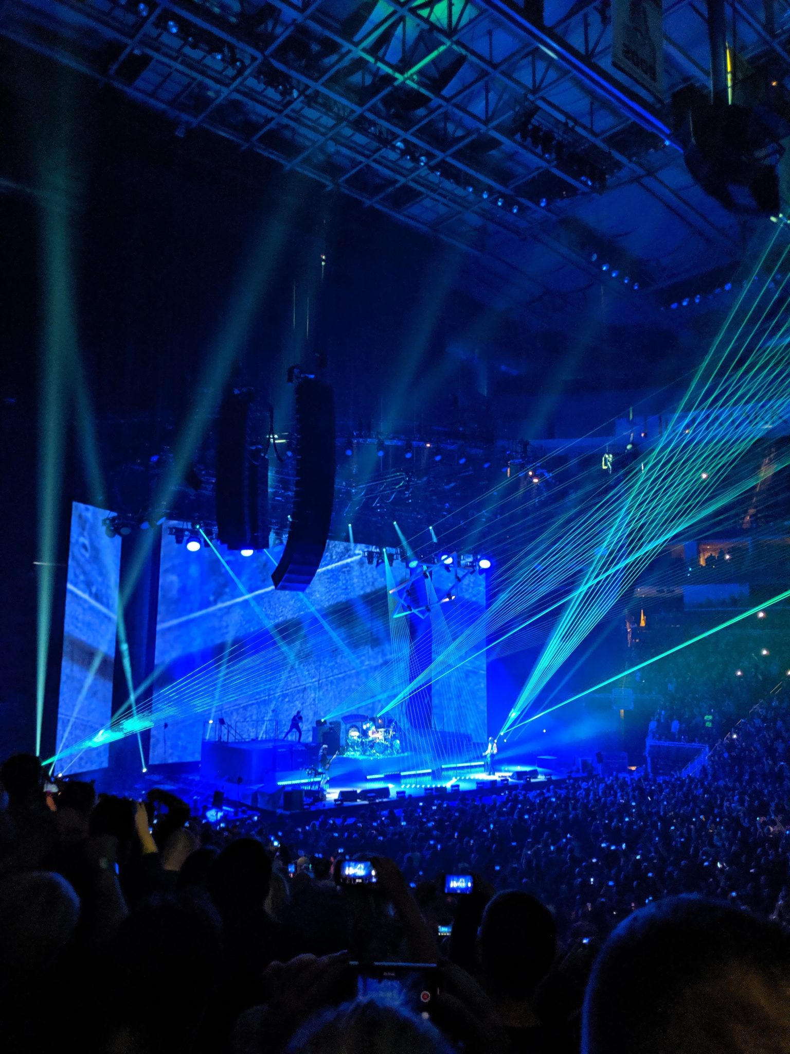 A concert stage shooting lights out into a dark arena.