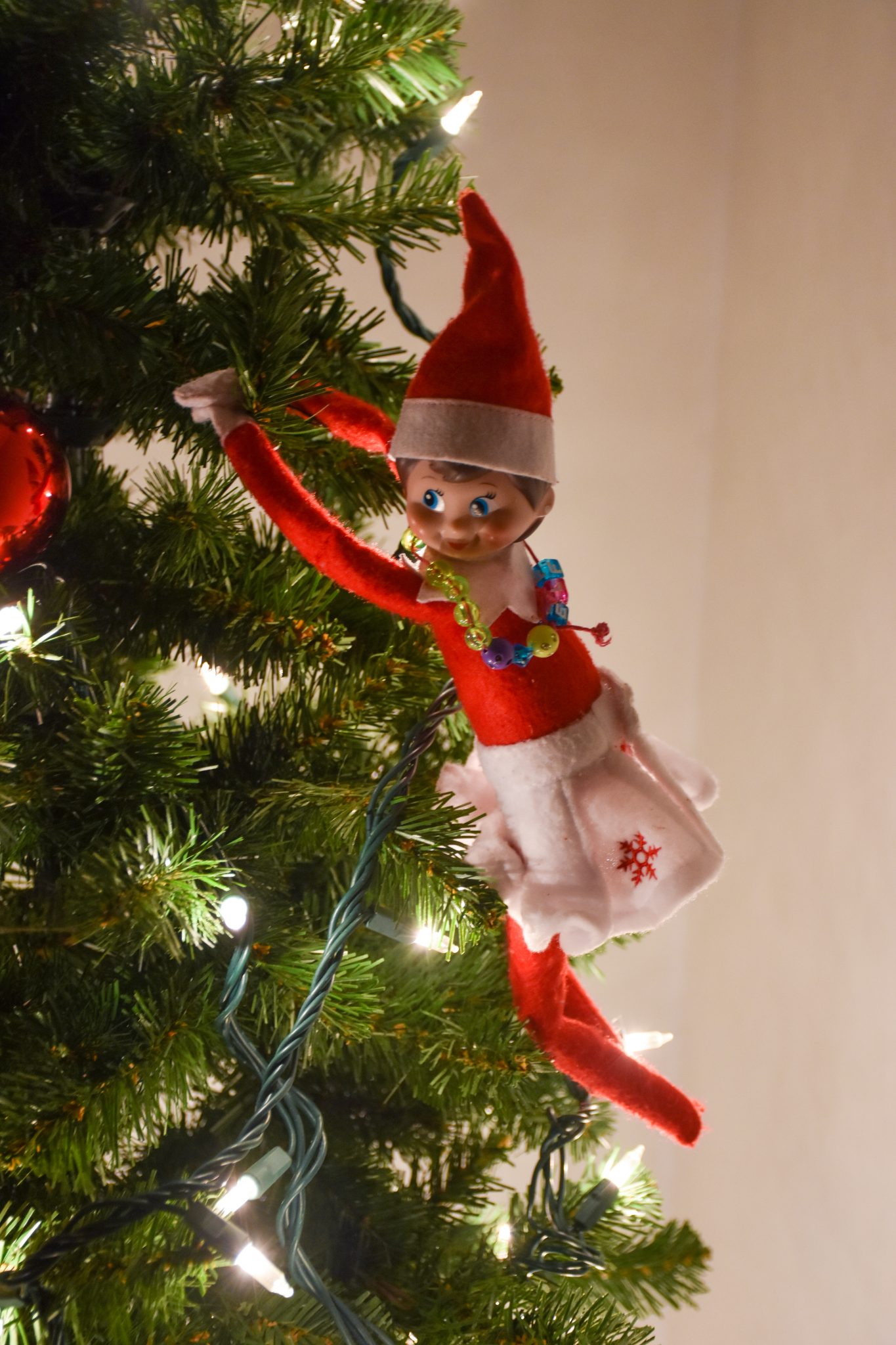 Elf on a shelf hanging from a Christmas tree