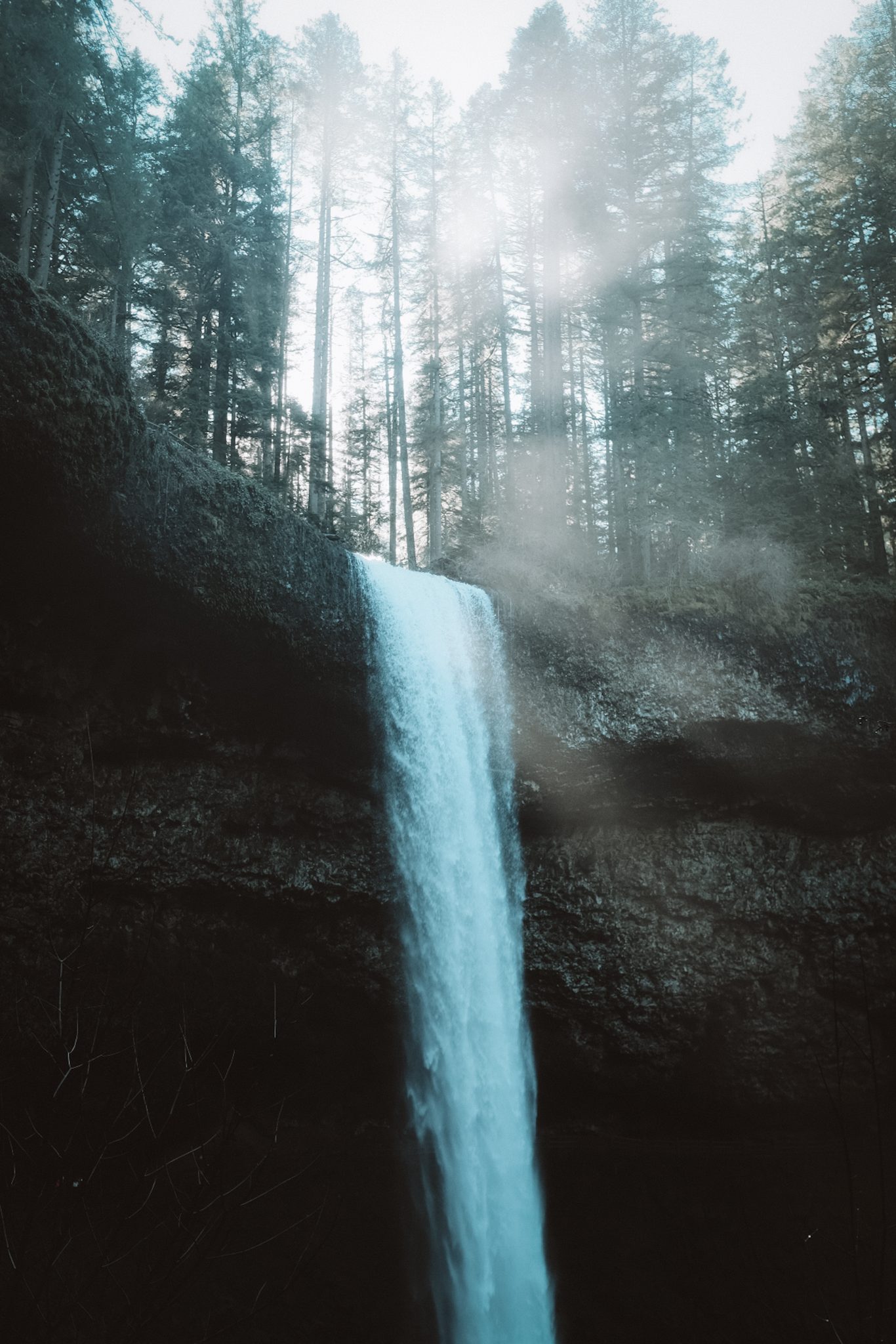 Light shining over top of a waterfall