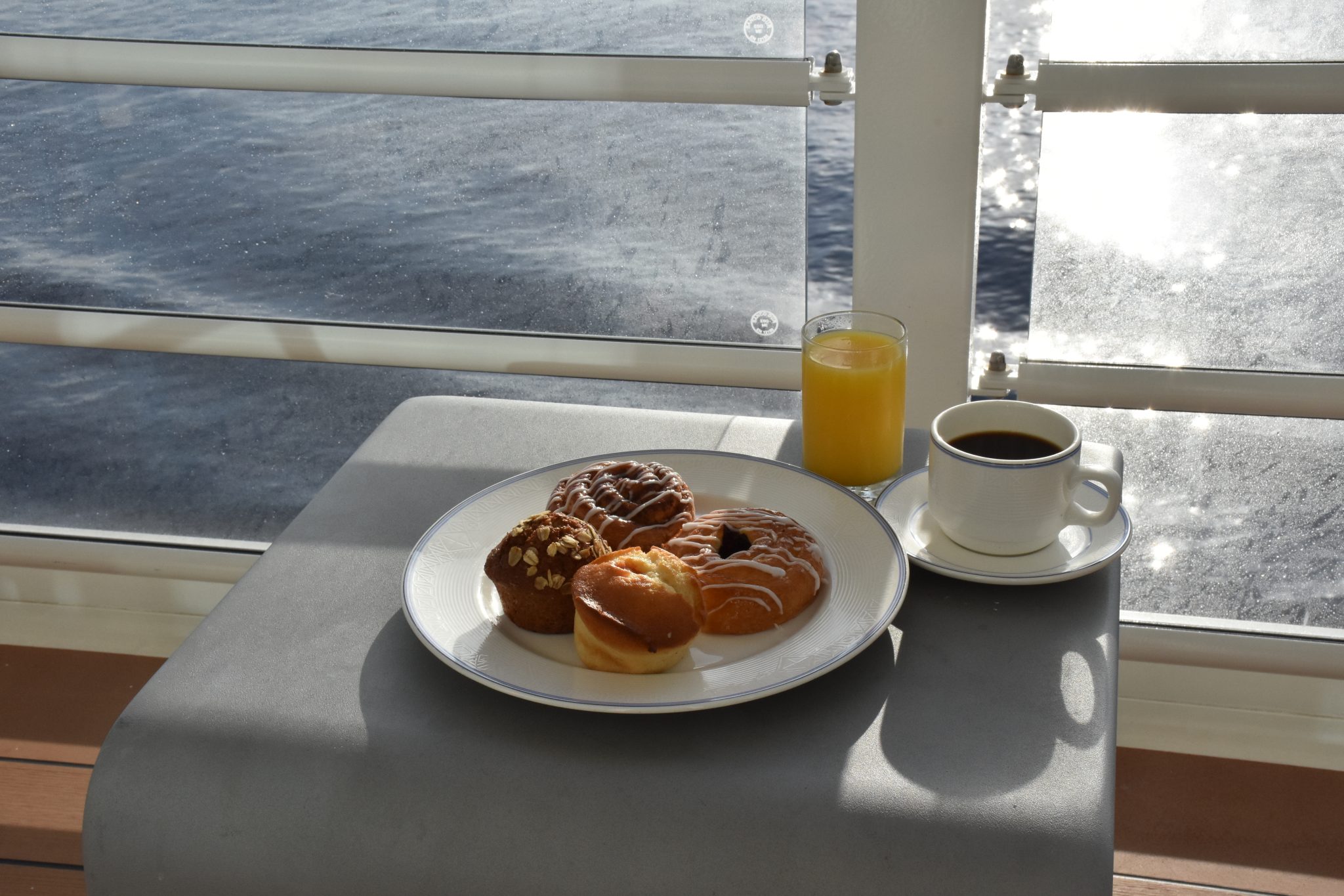 Breakfast pastries, orange juice, and coffee on a cruise ship balcony