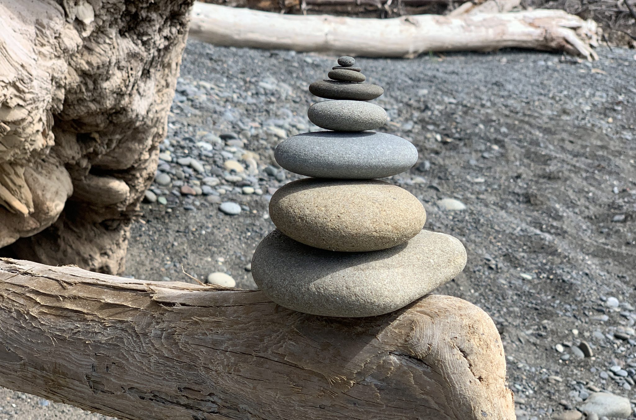 Stacked rocks balancing on driftwood.