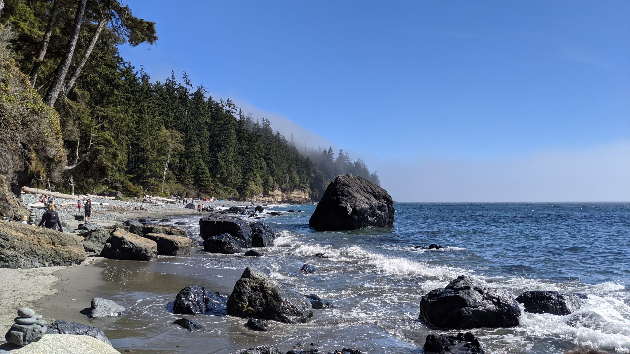 China Beach on Vancouver Island with waves breaking on large rocks and a cairn in the foreground