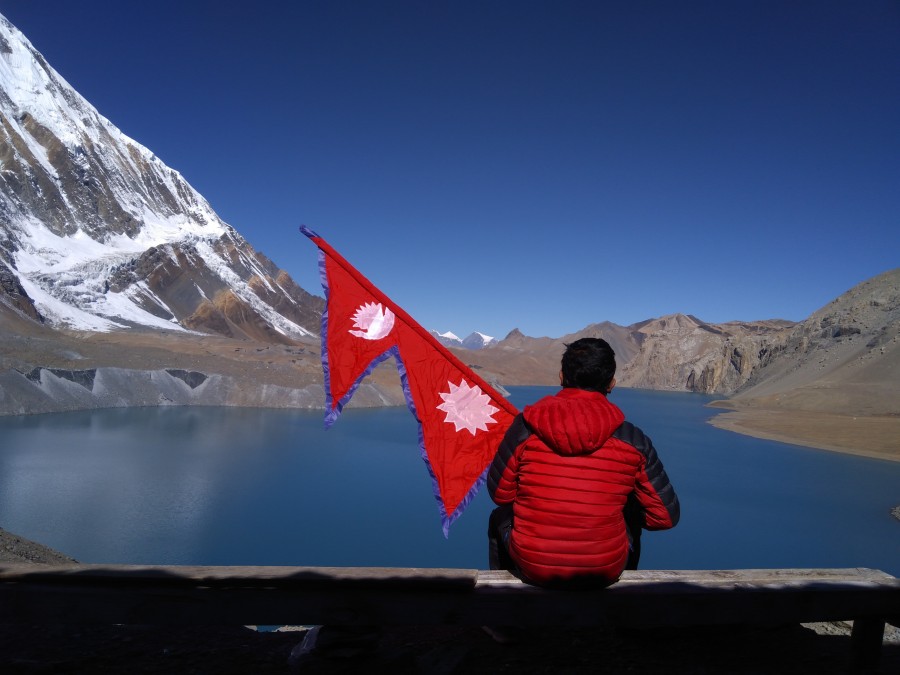 Man at Tilicho Lake with national flag