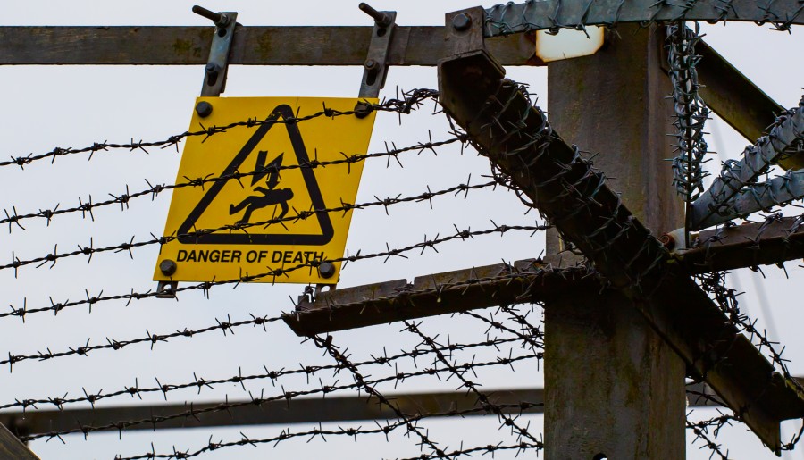 Danger of death sign behind barbed wire