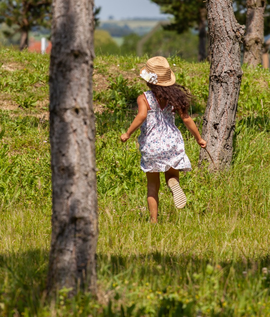 Child in hat running between trees